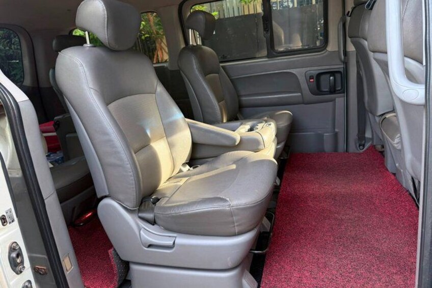 Een voertuiginterieur met grijze leren stoelen, een rood tapijt en een deur. 4