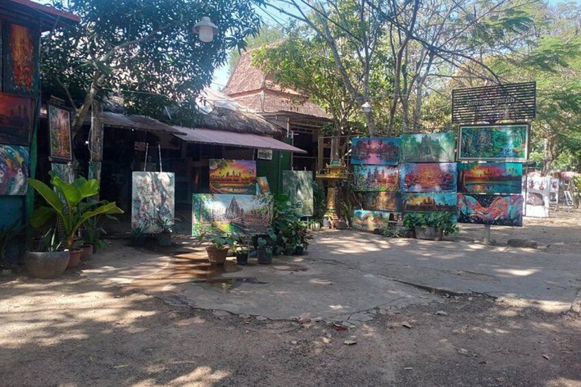 A street with colorful murals, a thatched-roof building, and potted plants. 2