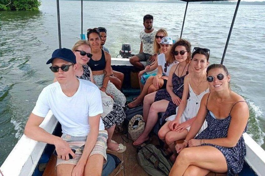 A group of people on a boat with a calm water body and greenery in the background. 2