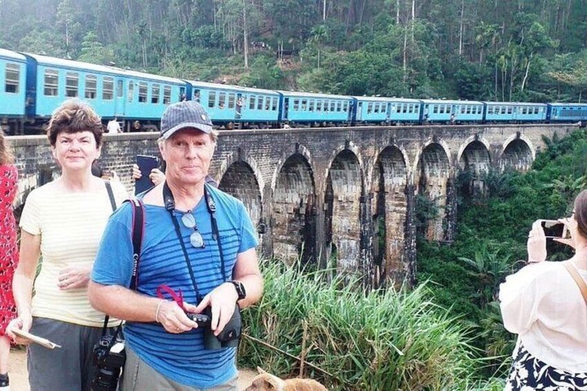 A train on a bridge, tourists observing, and a person taking a photo. 3
