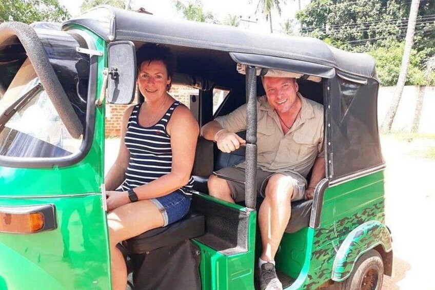 A green auto-rickshaw with two passengers, one in a striped tank top and denim shorts, the other in a light-colored shirt and shorts. 4