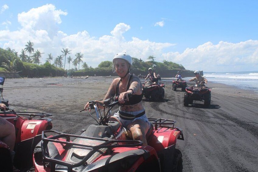 A group of people on ATVs on a beach with palm trees and ocean in the background. 5