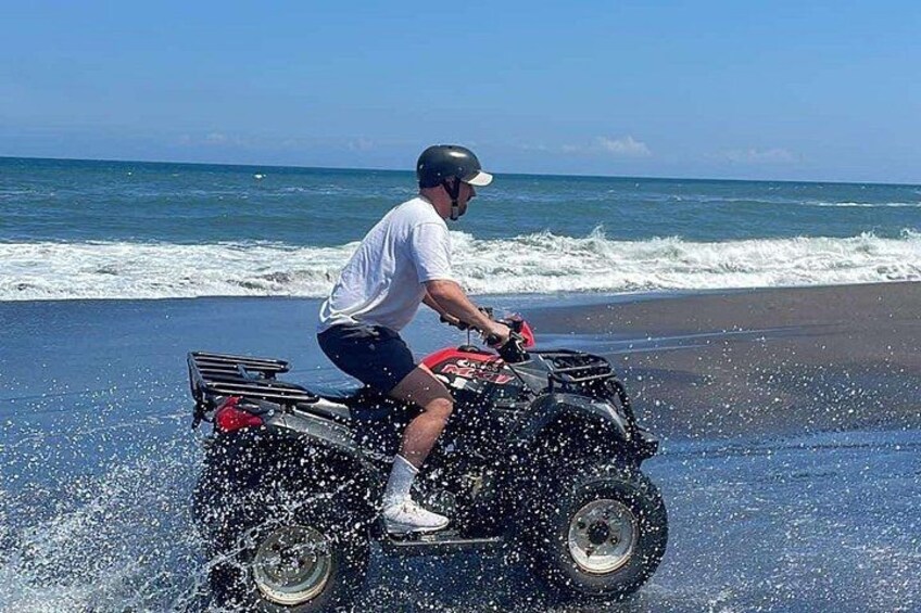 Una persona guida un ATV su una spiaggia, con le onde sullo sfondo. 2