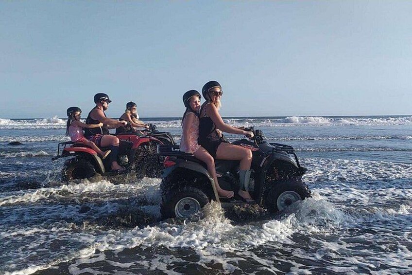 Menschen fahren mit Quads am Strand, Wellen im Hintergrund. 3