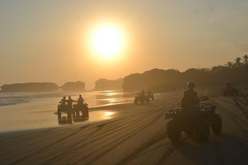 Ein Sonnenuntergang über einem Strand, auf dem Menschen mit Quad fahren. 5