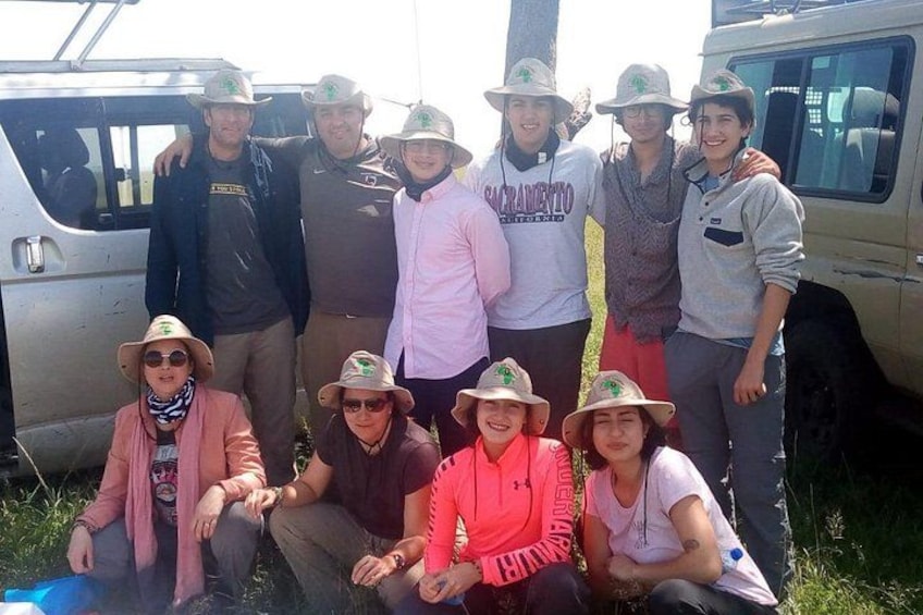A group of people in outdoor attire posing in front of a vehicle. 3