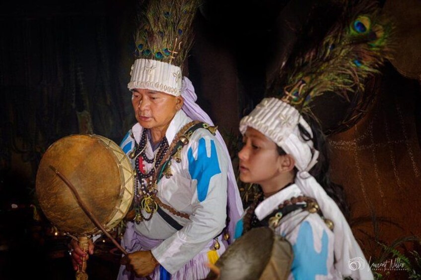 Deux personnes, vêtues de costumes traditionnels et coiffées de cocardes ornées de plumes, dont l’une joue du tambour. 1