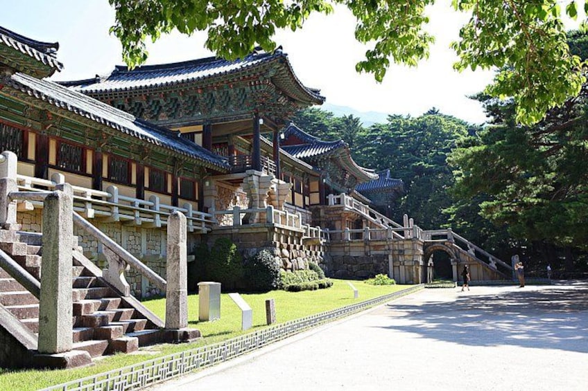 A traditional Korean palace with ornate architecture, a stone staircase, and a well-maintained garden. 3