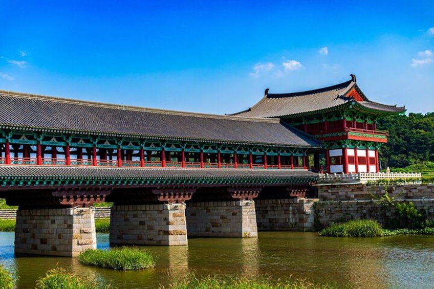 A traditional Korean bridge with ornate architecture, a stone foundation, and a clear blue sky. 4