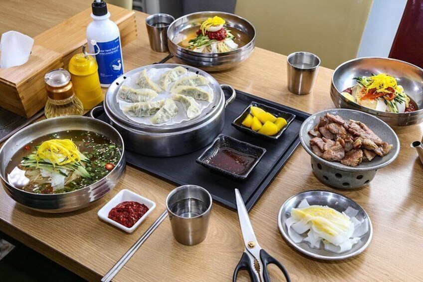 Ein Tisch mit verschiedenen Gerichten, darunter Knödel, Fleisch und eine Schüssel Suppe. 4