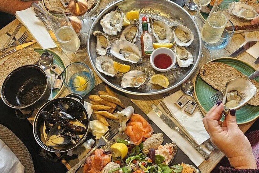 Un plateau de fruits de mer comprenant des huîtres, des moules et du saumon, servi avec du pain et des boissons. 3