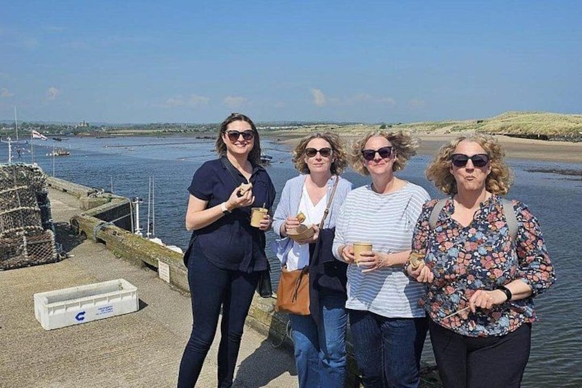 Four people standing by a waterfront with a clear sky. 2