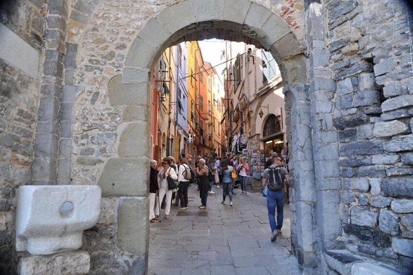 Un arco in pietra con persone che percorrono una stretta via fiancheggiata da edifici colorati. 2