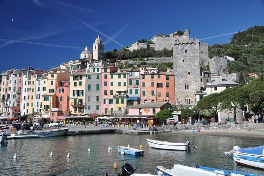 A coastal town with colorful buildings, a castle, and boats in the water. 2