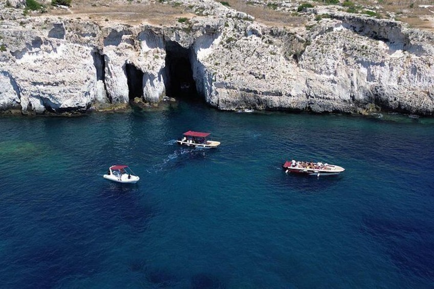 Tres embarcaciones en un mar azul y despejado, con acantilados rocosos al fondo. 2