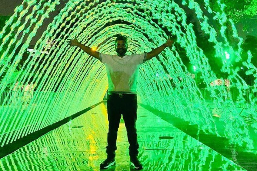 Una persona in piedi in un tunnel illuminato da motivi di luce verde. 5