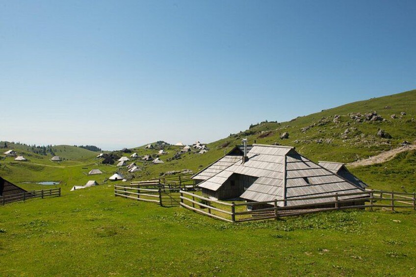 A rural landscape with traditional wooden houses, a wooden fence, and a clear blue sky. 4