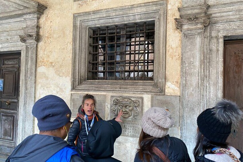 A group of people standing in front of a building with a window and a door. 3