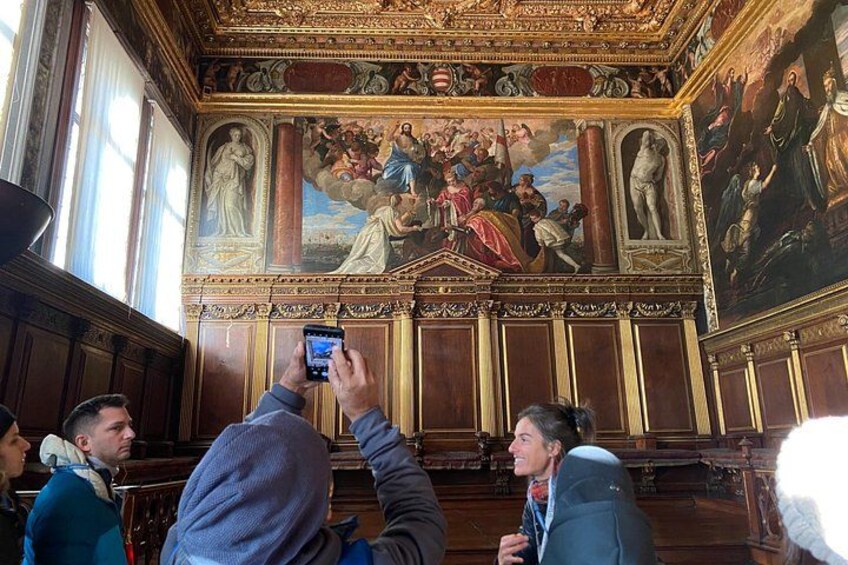 Una stanza con pannelli in legno finemente decorati e un grande affresco sulla parete. 4