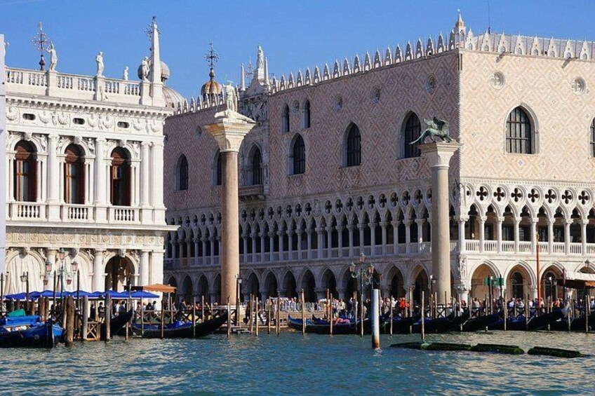 A historic Venetian building with ornate architecture, a canal with boats, and a clear blue sky. 3