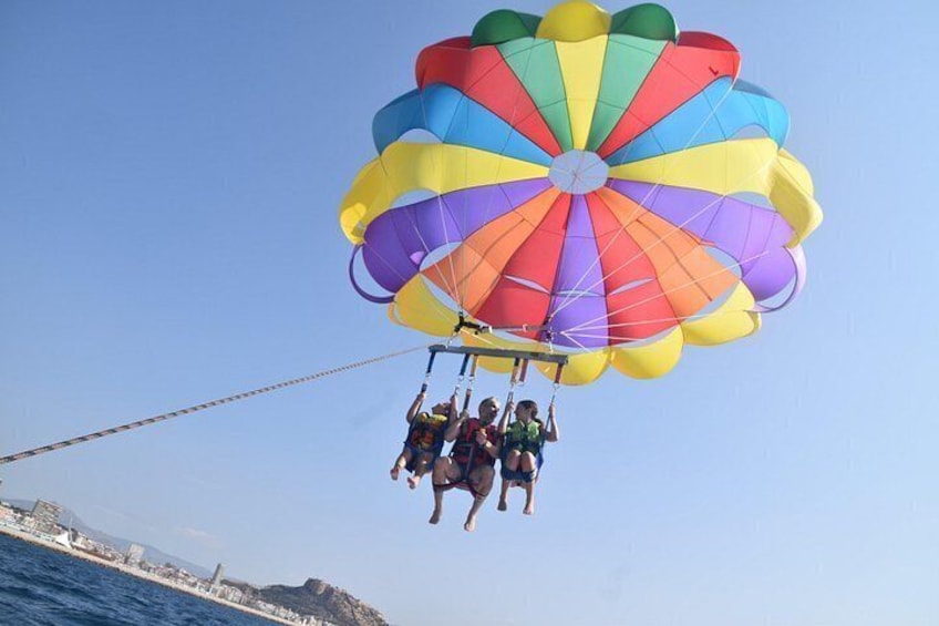 Un grupo de personas parapentando sobre el agua con un paracaídas colorido. 4