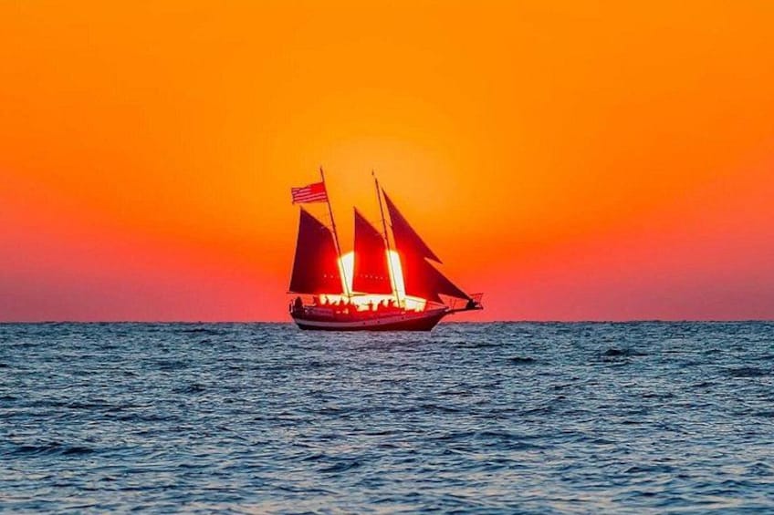 Un velero con dos banderas en un mar tranquilo al atardecer. 4