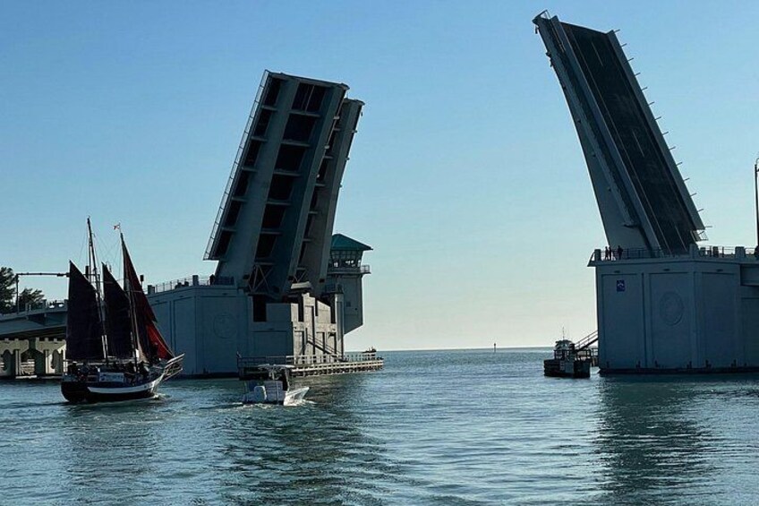 Un puente con dos grandes secciones, un velero y un pequeño barco a motor en el agua. 3