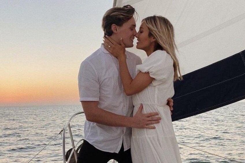 Una pareja se abraza en un velero al atardecer. 2