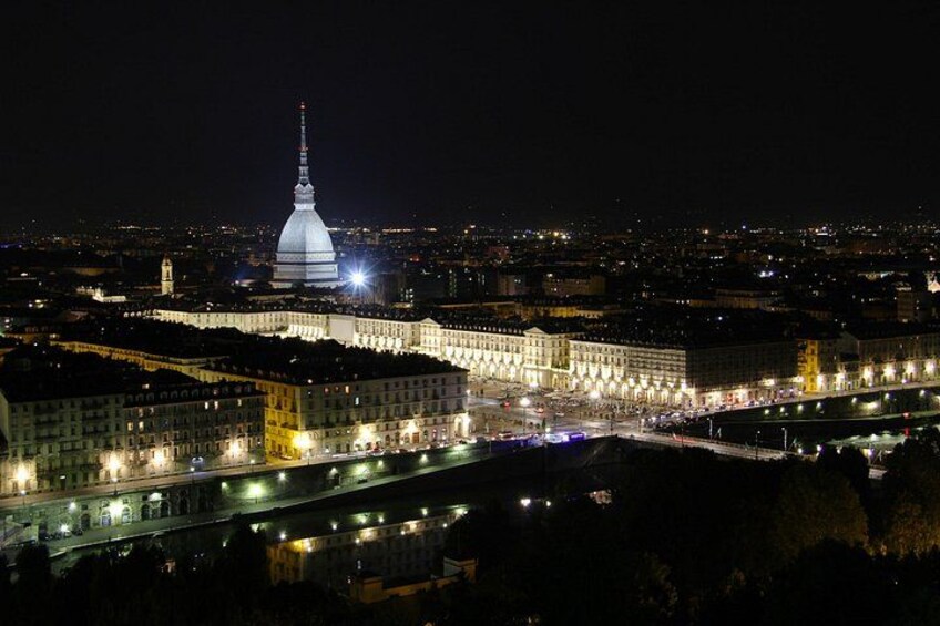 Une vue nocturne d’une ville, avec des bâtiments illuminés, une tour imposante et une rivière. 2