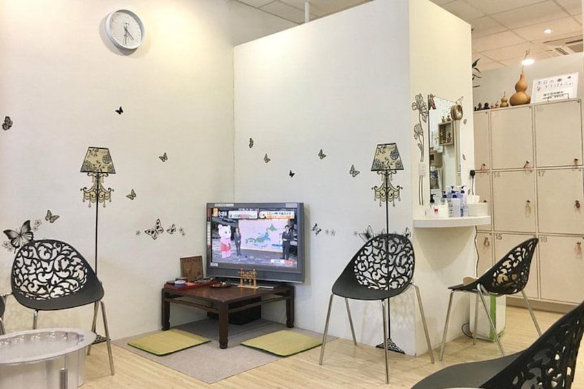 Un soggiorno con televisione, due poltrone, un tavolino e decorazioni murali a forma di farfalla. 1