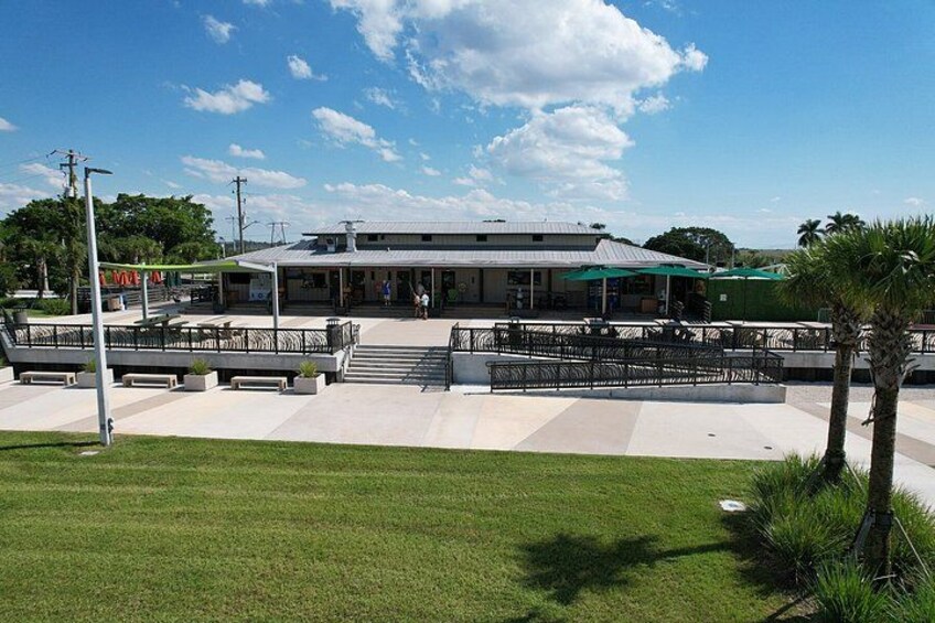 A public building with a covered patio area, a grassy lawn, and a palm tree. 2