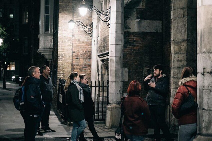 Een groep mensen staat 's nachts op een voetpad, verlicht door straatverlichting. 2