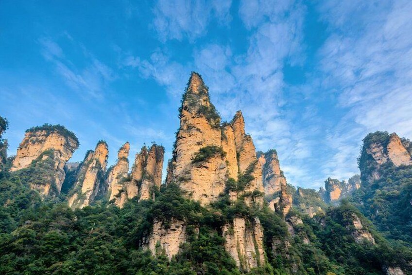 A mountainous landscape with tall, rugged rock formations and dense green vegetation. 5