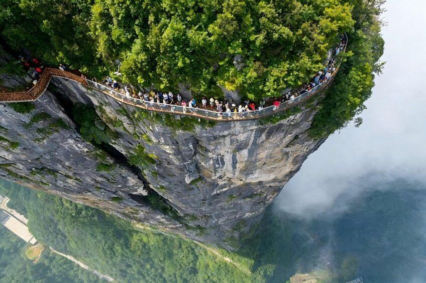 A suspension bridge with people walking across it, surrounded by lush greenery and steep cliffs. 2