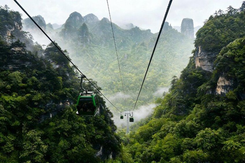 A cable car system in a mountainous area with dense green foliage and rocky cliffs. 4