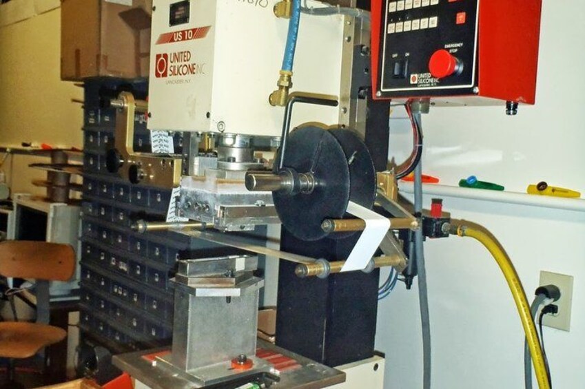 A machine with a control panel, a spool of black material, and a metal structure. 2