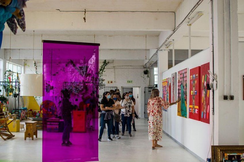 Una galería de arte interior con gente observando obras de arte. 2
