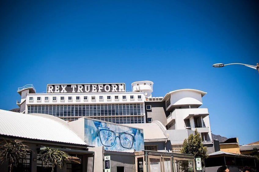 A building with the sign 'REX TRUEFORM' and a mural of glasses on its facade. 3