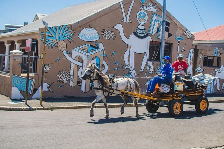 Un coche de caballos frente a un edificio con un mural. 3