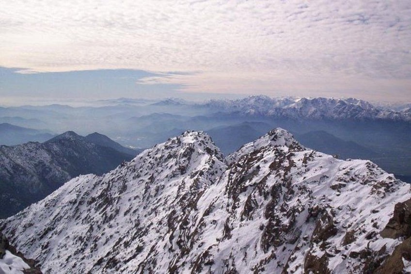 A snow-covered mountain peak with rugged terrain and distant mountain ranges. 3
