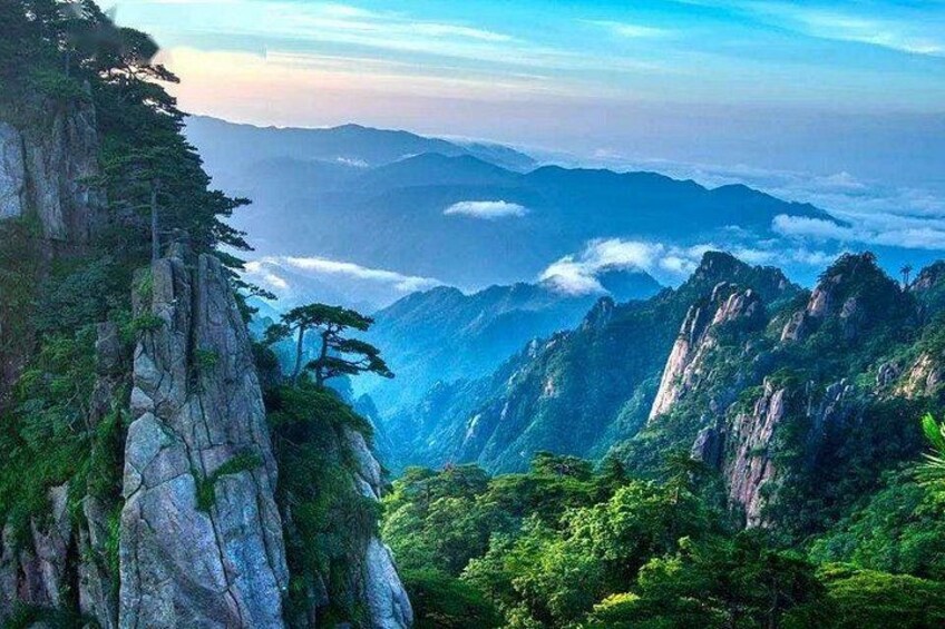 A mountainous landscape with dense green foliage and rocky cliffs. 3