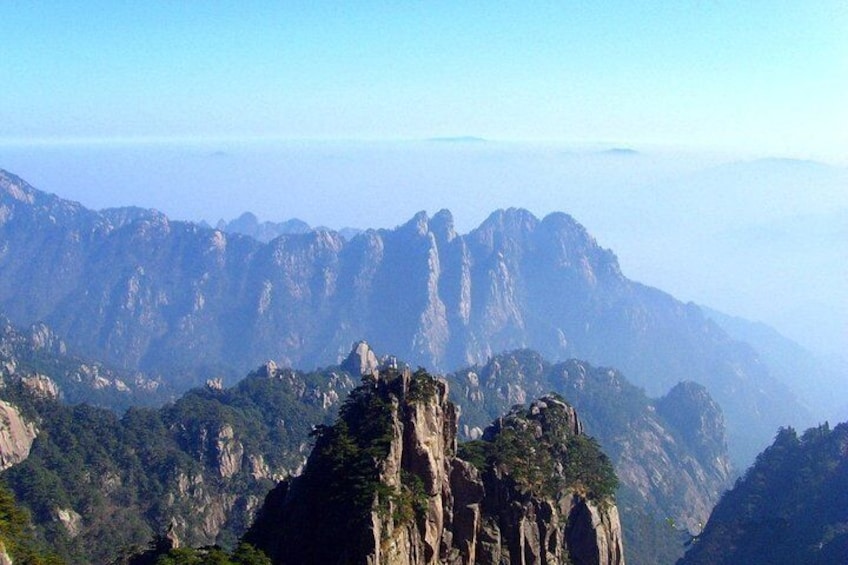 A mountainous landscape with prominent rock formations and dense forest. 3