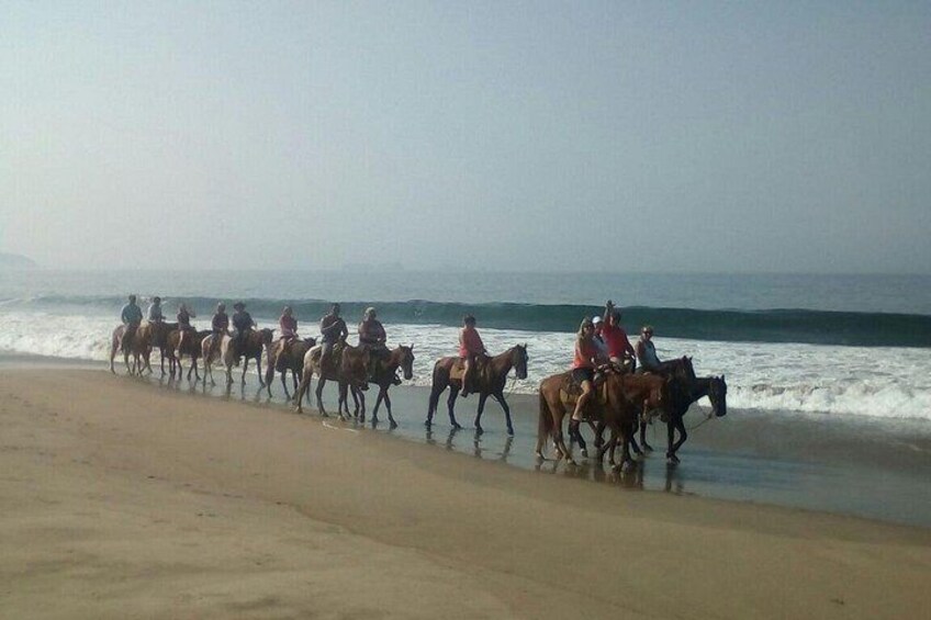 Un groupe de personnes à cheval, se promenant le long d’une plage. 5
