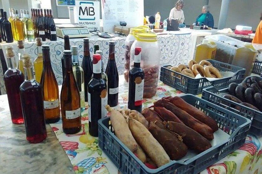 A table with various bottles, jars, and baskets of food items. 3