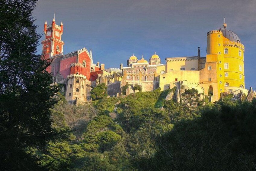 A historic castle with red and yellow buildings, domed structures, and a tower. 1