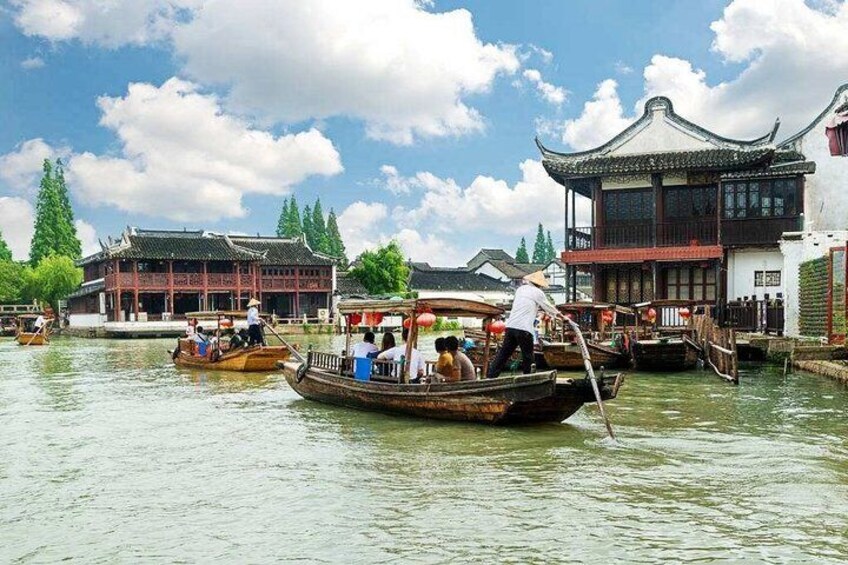 Eine traditionelle Bootsfahrt auf einem Fluss mit Passagieren und einem Führer, umgeben von historischen Gebäuden. 5
