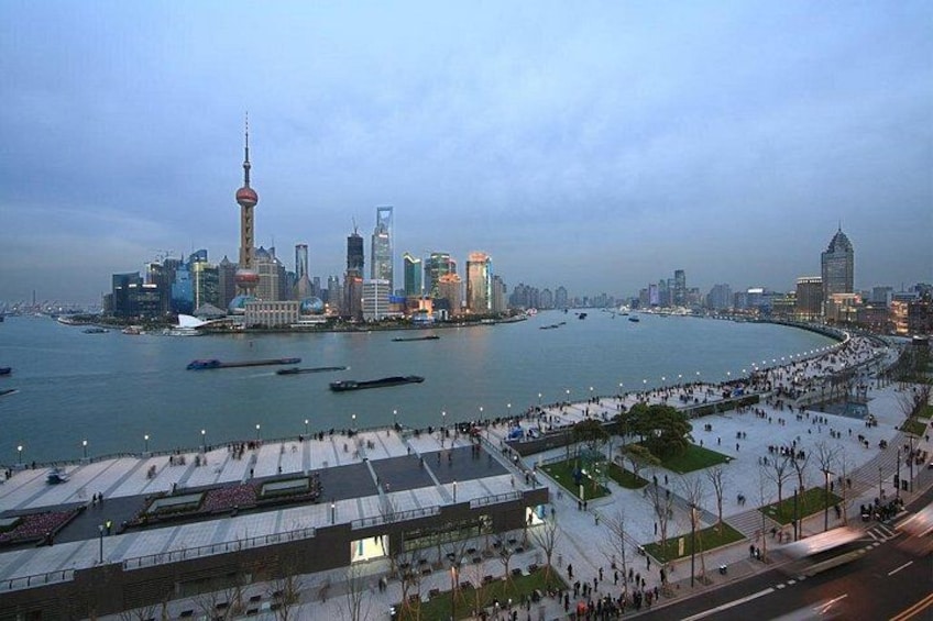 A waterfront cityscape with a prominent tower, a curved road, and a promenade. 4