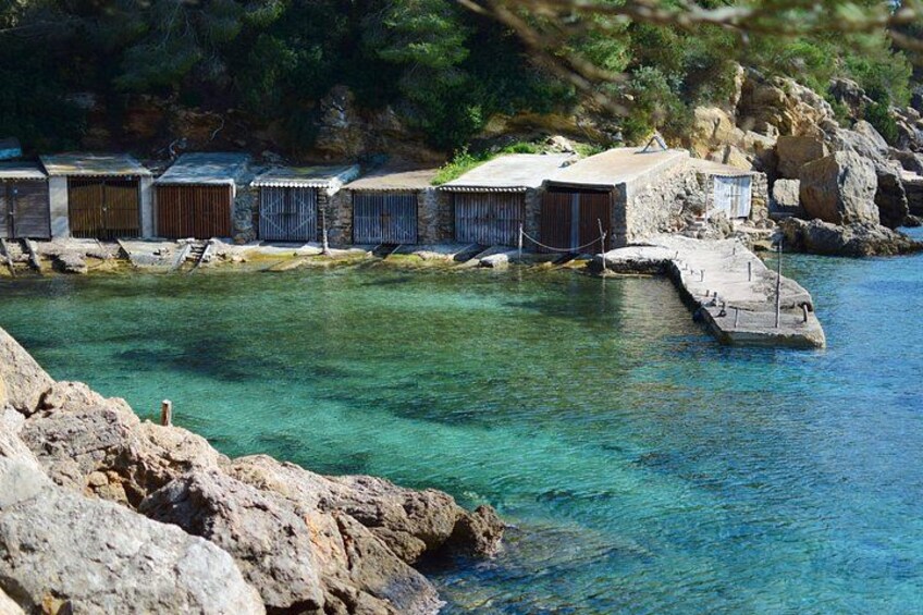 A coastal area with clear water, rocky terrain, and wooden structures. 1