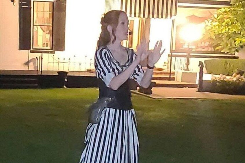 Una persona con un vestido a rayas está de pie en un área con césped, con un edificio al fondo. 2
