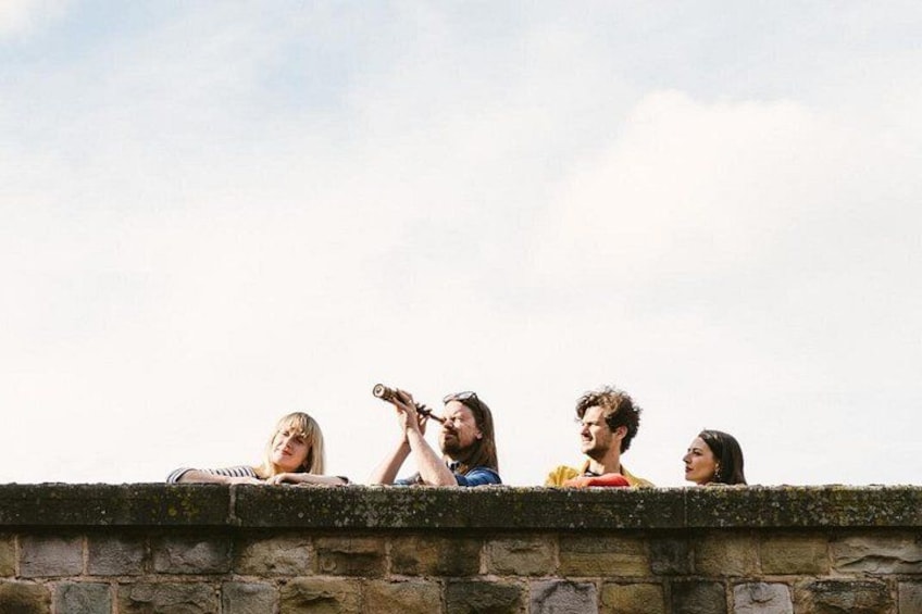 Four people sitting on a stone wall. 4